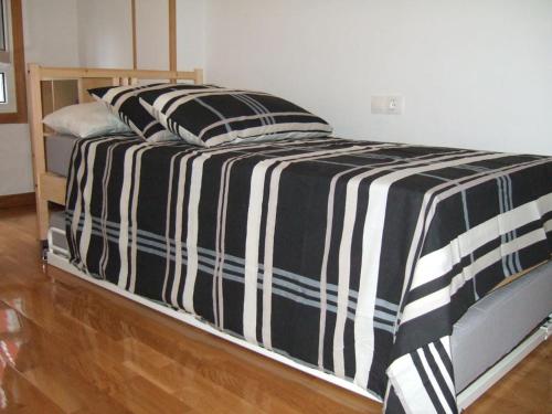 a bed with a black and white striped comforter at Apartamento en 1ª línea de la Playa de Covas - Viveiro (Lugo) in Viveiro