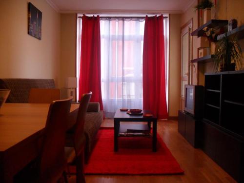a living room with a table and red curtains at Apartamento en 1ª línea de la Playa de Covas - Viveiro (Lugo) in Viveiro
