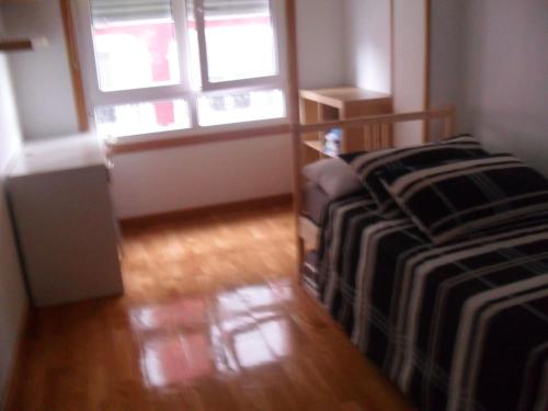 a bedroom with a bed and two windows and a wooden floor at Apartamento en 1ª línea de la Playa de Covas - Viveiro (Lugo) in Viveiro