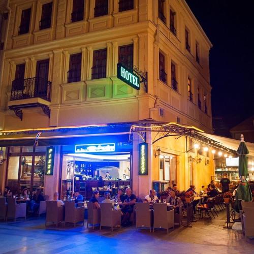 eine Gruppe von Menschen, die an Tischen vor einem Gebäude sitzen in der Unterkunft Hotel Treff in Bitola