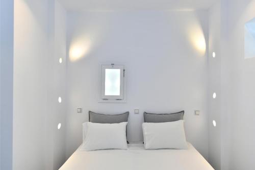 a bedroom with white walls and a bed with two pillows at Lorenzo Studios and Suites Paros in Naousa