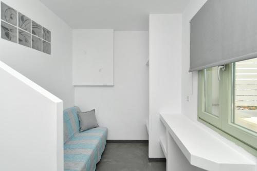 a living room with a blue couch and a window at Lorenzo Studios and Suites Paros in Naousa