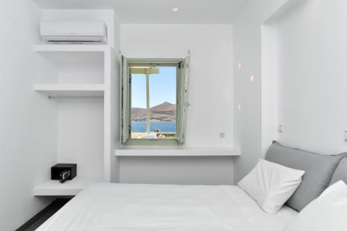 a white room with a window and a bed at Lorenzo Studios and Suites Paros in Naousa