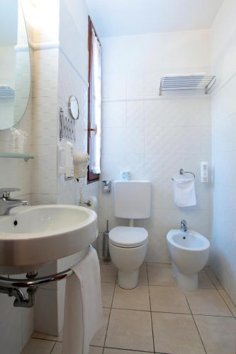 a white bathroom with a toilet and a sink at Hotel Centrale in Bologna