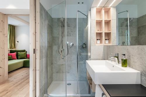 ein Bad mit einer Dusche mit einem Waschbecken und einer Duschkabine aus Glas in der Unterkunft Hotel Drumlerhof in Sand in Taufers