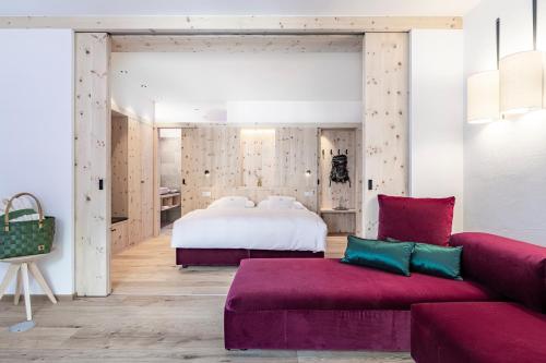 カンポ・トゥーレスにあるHotel Drumlerhofのベッドルーム(ベッド1台、紫色のソファ付)
