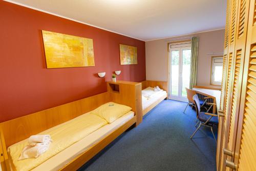 a hotel room with two beds and a desk at Wilhelm-Kempf-Haus in Wiesbaden