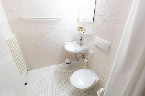 biała łazienka z toaletą i umywalką w obiekcie Wilhelm-Kempf-Haus w mieście Wiesbaden
