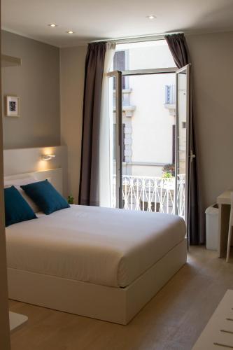 a bedroom with a large bed and a balcony at Le Suite del Corso in Syracuse