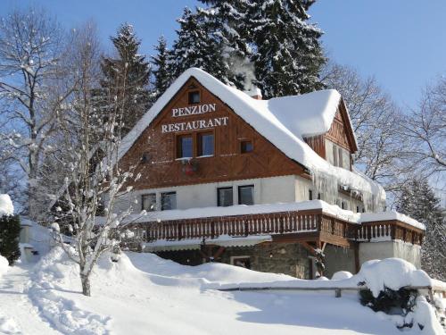 a log cabin in the snow with snow covered trees at Pension & Restaurant Krakonoš in Harrachov