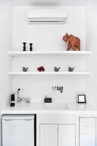 a white kitchen with white shelves and an elephant figurine at 21 luxury apartments in Naousa