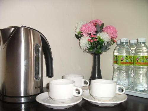 una macchinetta del caffè, due tazze e un vaso con fiori di Swiss Hotel Kuala Lumpur a Kuala Lumpur