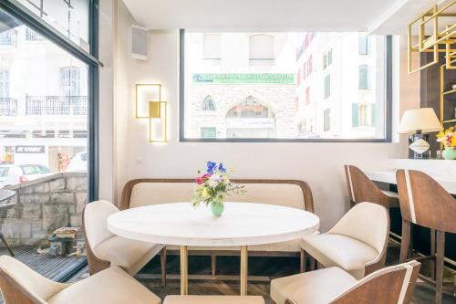 a white table in a room with chairs and a vase of flowers at Hôtel Cosmopolitain in Biarritz