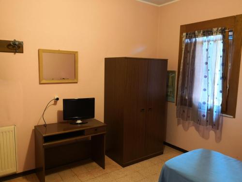 una camera da letto con televisore e comò con armadio di Trattoria Bar Oasi a Pocenia