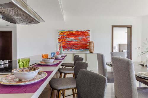 a dining room with a table with chairs and a painting at Mareazul Beach Front Condos At playa del Carmen in Playa del Carmen