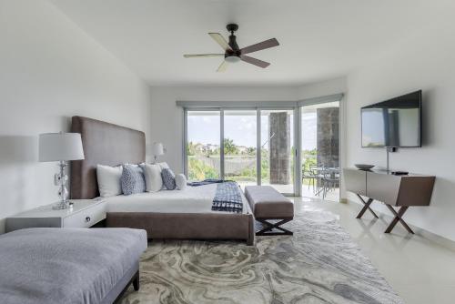 a white bedroom with a bed and a flat screen tv at Mareazul Beach Front Condos At playa del Carmen in Playa del Carmen
