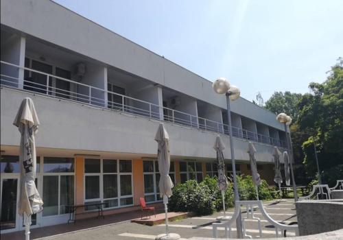 a hotel with tables and umbrellas in front of it at Sport Hotel in Tatabánya