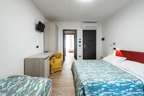 una habitación de hotel con 2 camas y una silla amarilla en Hotel Ristorante Vecchia Maremma, en Orbetello