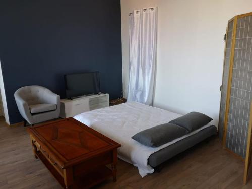 una camera con letto, sedia e televisore di Appartement Spacieux et confortable a Châteaubourg