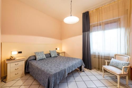a bedroom with a bed and a chair and a window at Hotel Ristorante Vecchia Maremma in Orbetello