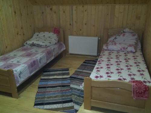 two beds in a room with wooden walls at Відпочинок у Карпатах, мінеральні ванни, банний Чан! in Verkhniy Bystryy