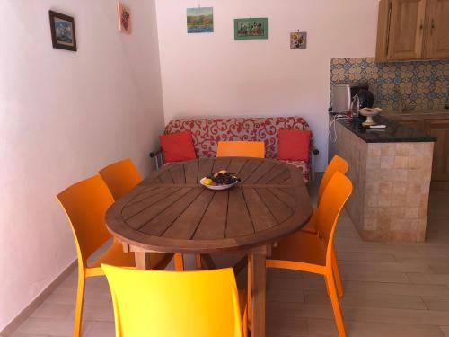 a dining room table and chairs with a bowl of fruit on it at Appartamenti Cala Azzurra in Scopello