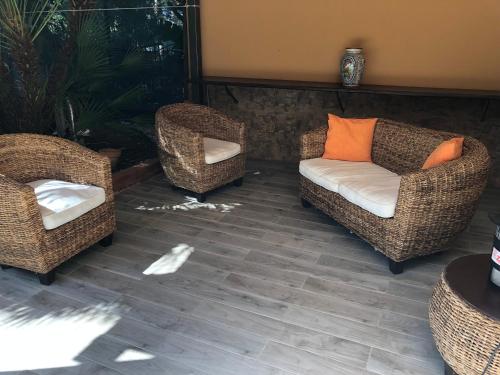 three wicker chairs and a couch on a patio at Appartamenti Cala Azzurra in Scopello
