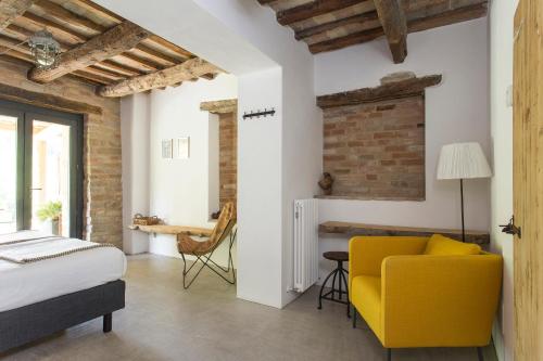 Agriturismo Unico Senso في Montottone: غرفة نوم بسرير وكرسي اصفر