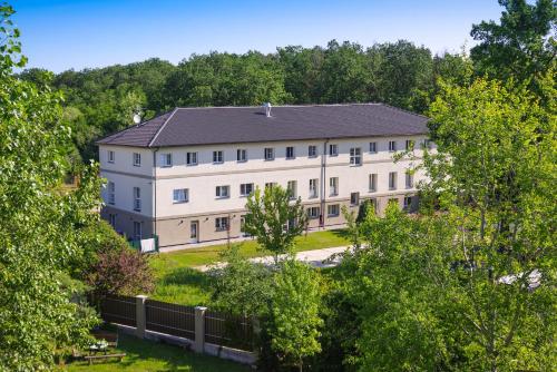 a large white building with a black roof at Penzion Lesni in Milovice