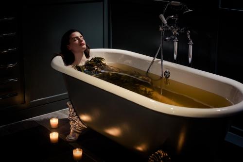Osprey Hotel في ناس: امرأة تقف في حوض الاستحمام مع الشموع
