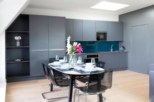 a dining room with blue cabinets and a table with flowers at Hampden Apartments - The Richard in Windsor