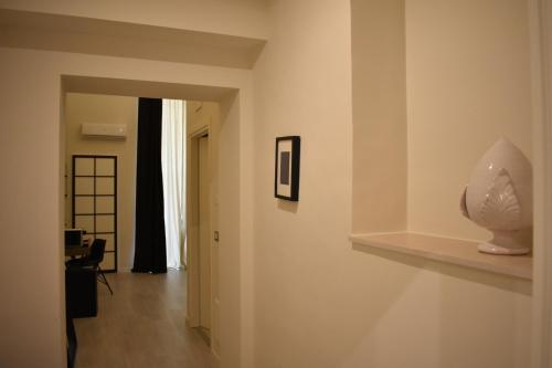 a hallway with a white wall with a vase on a shelf at Gatto Bianco Duchessa in Bari
