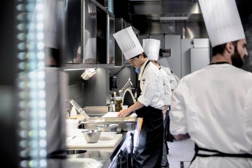 two chefs standing in a kitchen preparing food at Hotel Plaza e de Russie - Relais & Châteaux in Viareggio
