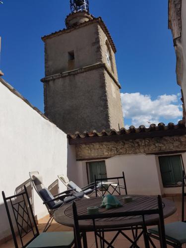 a table and chairs on a balcony with a tower at La Maison Provençale in La Roquebrussanne