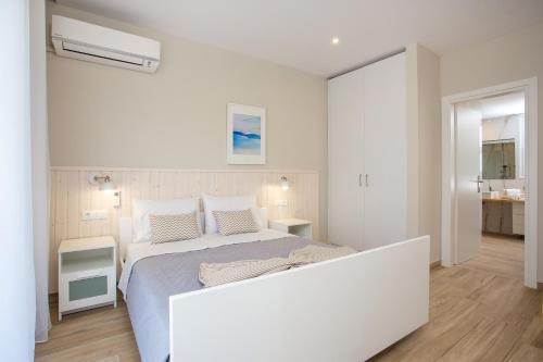 a white bedroom with a large bed and a bathroom at Avi Suites Faliraki in Faliraki