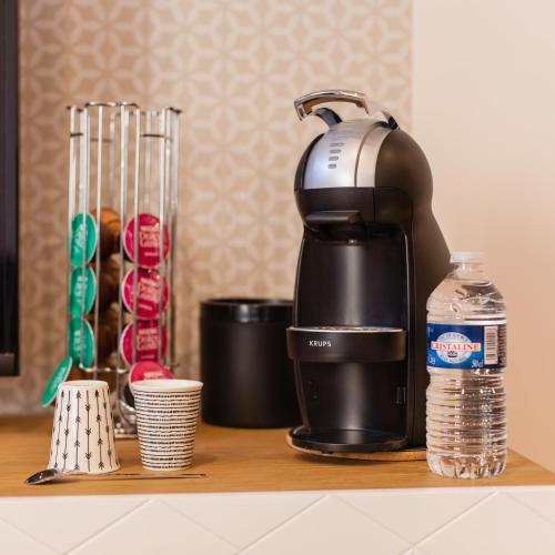 a coffee maker sitting on a counter next to a bottle of water at Legend - Le Saint Laurent - Parking - Wifi - 24/7 - cosy in Saint-Laurent-sur-Saône