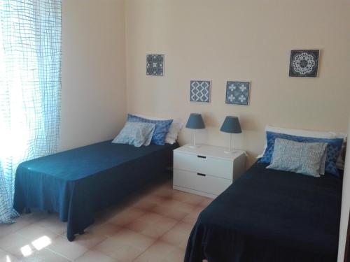 1 dormitorio con 2 camas con sábanas azules y ventana en La Casa del Geco, en Casarza Ligure