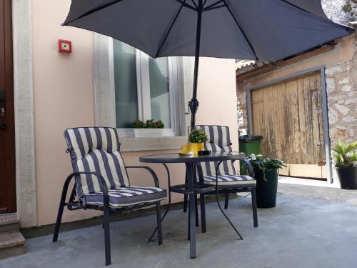 two chairs and a table with an umbrella on a patio at Apartments Paris in Umag