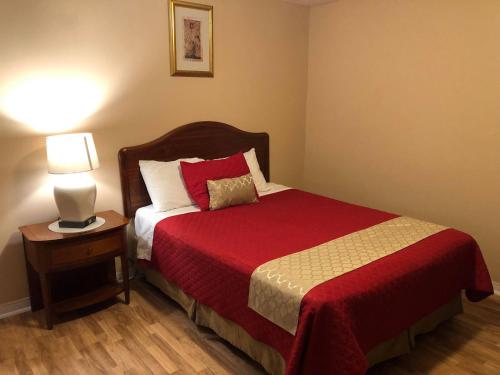 a bedroom with a bed with a red blanket and a lamp at Niagara Inn & Suites in Niagara Falls