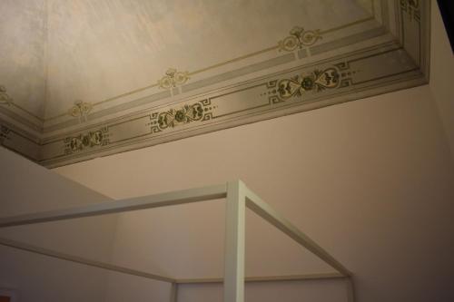 a white wall with a ceiling with gold embellishment at Gatto Bianco Duchessa in Bari