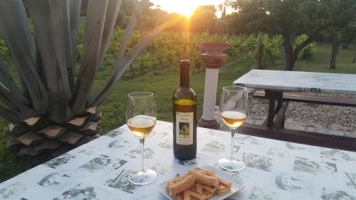 a table with a bottle of wine and two glasses at SERRA E MESU Affittacamere in Magomadas