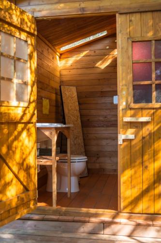 a bathroom with a toilet in a wooden cabin at Tulpa Cádiz in Malcocinado
