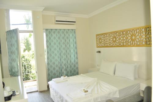 a bedroom with a white bed and a window at Kemer Park Otel in Kemer