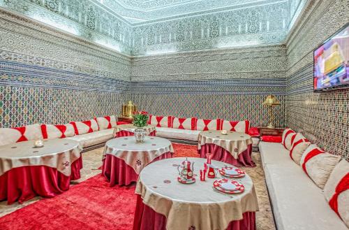 Zimmer mit roten Stühlen, Tischen und einer Decke in der Unterkunft Riad Dar Essalam in Marrakesch