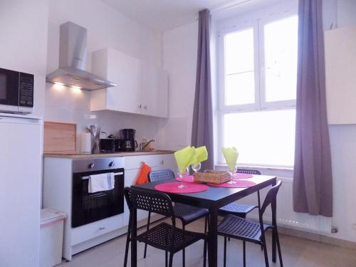 uma cozinha com uma mesa e cadeiras pretas e uma janela em La Lodelinsartoise - Meublé de vacances 3 clés em Charleroi