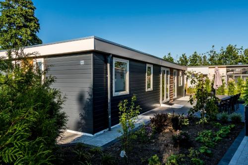 a black and grey tiny house with a garden at Chaletparc Krabbenkreek Zeeland - Chalet 94 in Sint Annaland