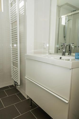 a white bathroom with a sink and a mirror at Chaletparc Krabbenkreek Zeeland - Chalet 94 in Sint Annaland
