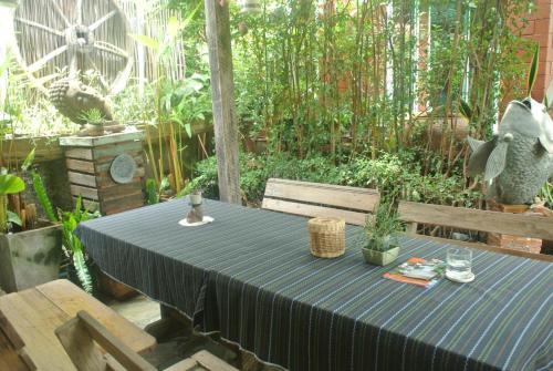 a table with a black table cloth sitting in a garden at P.Y. Guest House in Kanchanaburi