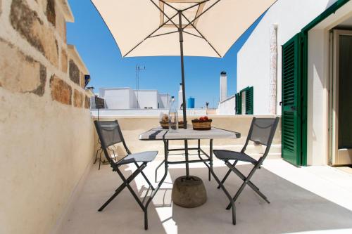 - une table et des chaises sur une terrasse avec un parasol dans l'établissement Il Galletto bb, à Patù