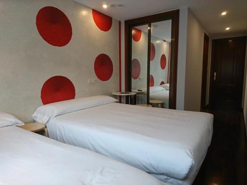 two beds in a room with red circles on the wall at Saudade Hostal Cafetería in A Coruña